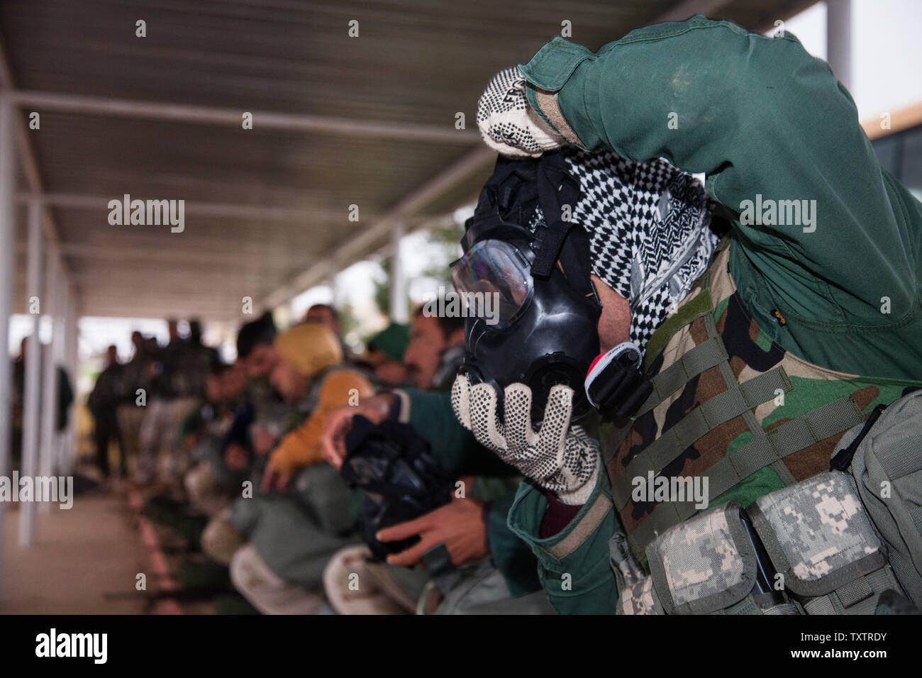 Peshmerga soldiers practice donning their protective masks while being timed by Italian instructors during a chemical biological radiological, and nuclear protection class near Erbil, Iraq, on March 28, 2016. Peshmerga soldiers attend the 10-week Modern Brigade Course, which begins with three weeks of basic infantry skills intended to improve their tactical knowledge to aid in the fight against the Islamic State of Iraq and the Levant. Erbil is one of four Combined Joint Task Force – Operation Inherent Resolve building partner capacity locations dedicated to training Iraqi Security Forces. Pho Stock Photo