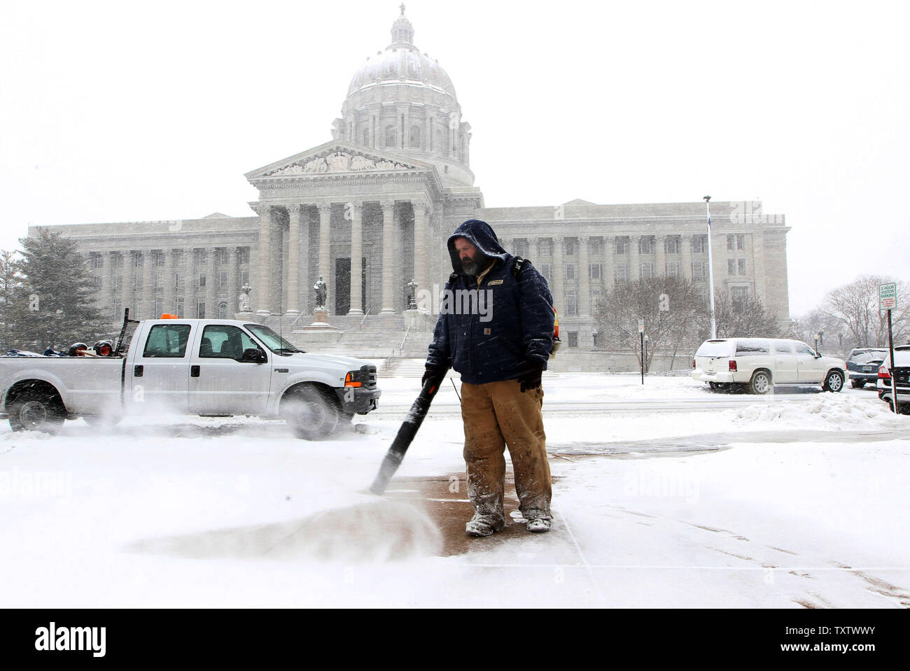 State employee Raleigh Nott uses a leaf blower to clear the sidewalks