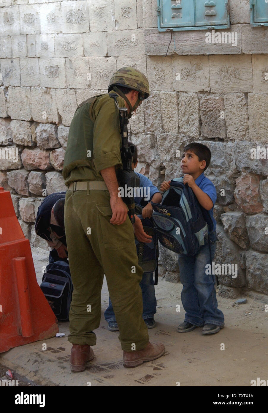 An Israeli soldier checks the schoolbag of a Palestinian boy at a checkpoint in the Biblical city of Hebron, October 14, 2003, traditionally believed to be the burial site of Abraham, Isaac, Jacob and their wives during the week long Jewish religious holiday of Sukkot. (UPI Photo/Debbie Hill) Stock Photo