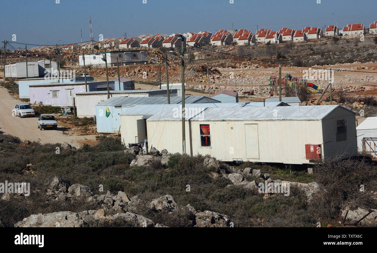 Houses in the Israeli settlement of Ofra loom above the caravans of the  unauthorized outpost settlement Ginot Aryeh, near Ofra, December 31, 2003. Residents of Ginot Aryeh received official eviction notices on Tuesday from the Israeli government as part of a plan to dismantle four outpost settlements in the West Bank. Spellman came to the outpost from her home in the Golan Heights to give support to her son who faces possible eviction. (UPI Photo/Debbie Hill) Stock Photo