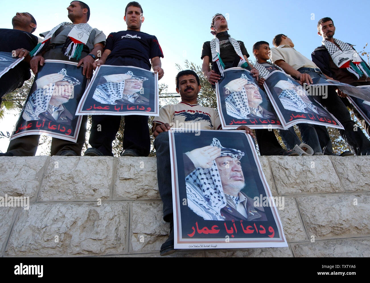 Palestinians holds posters of Yasser Arafat during his funeral in the