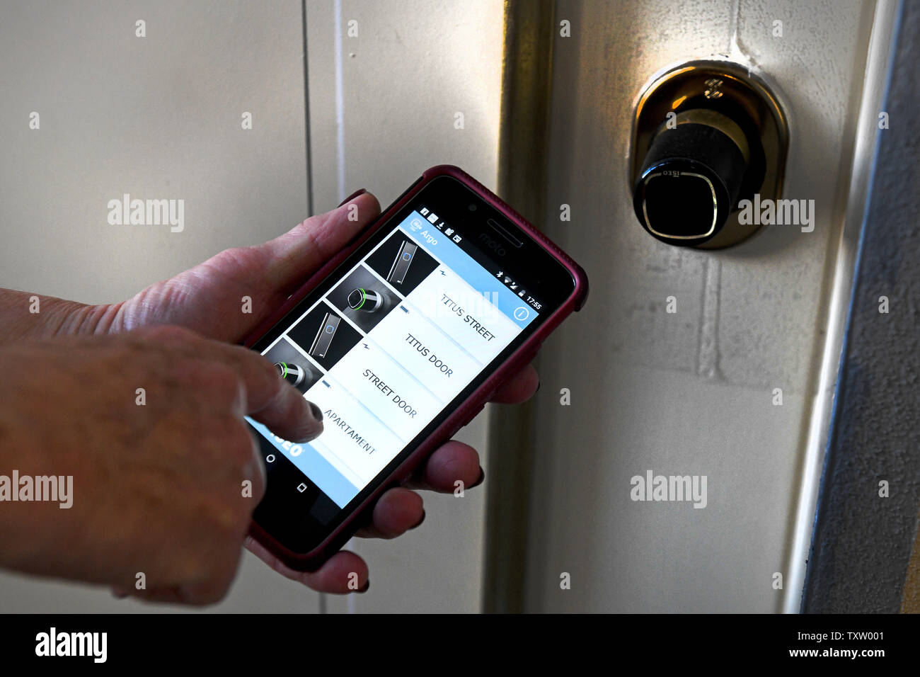 Unlocking opening apartment door with smartphone app using ISEO Argo Smart Locking app Stock Photo