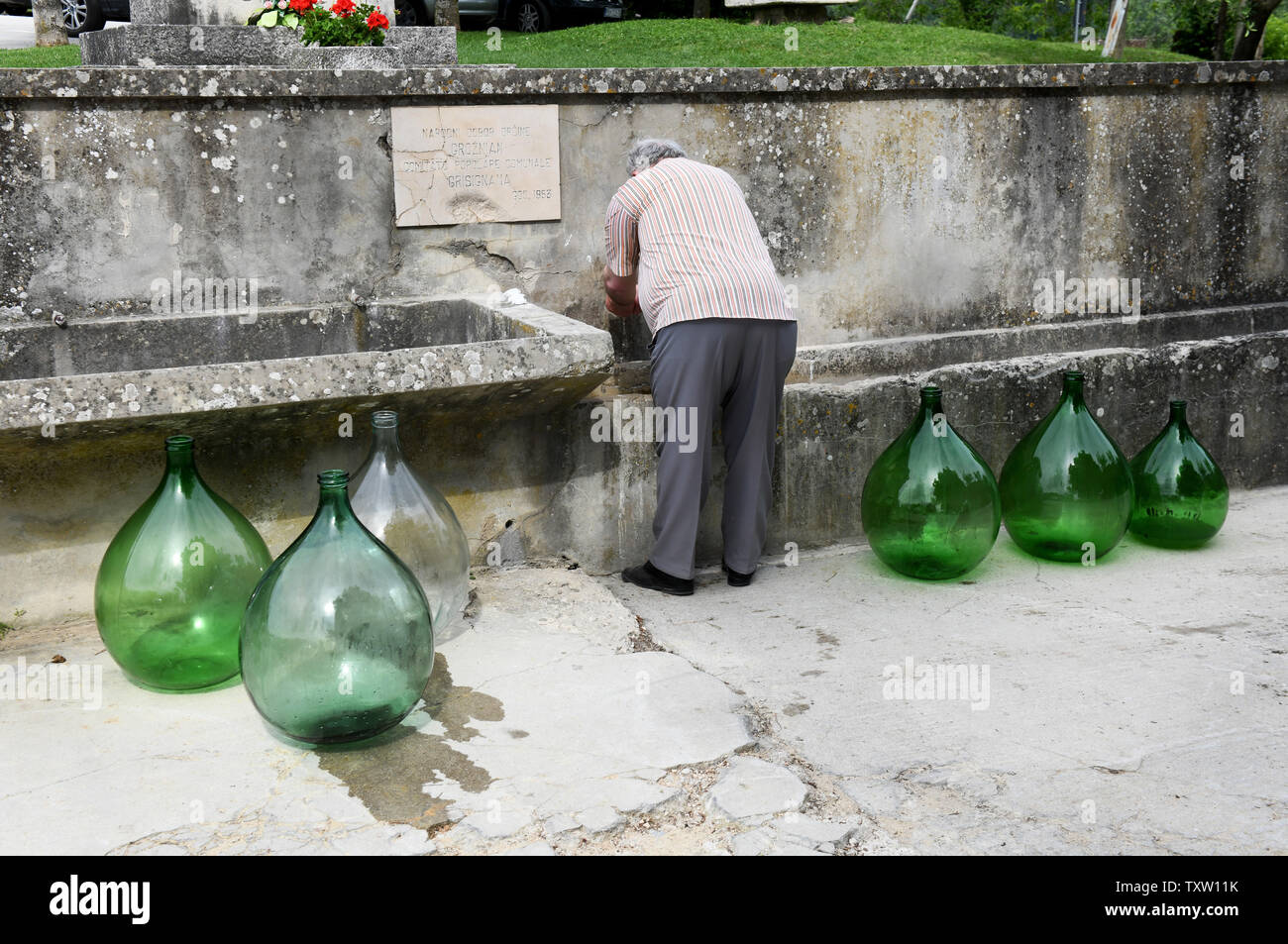 Washing cleaning large green glass distillery bottles Groznjan the hilltop village famous for it's truffles in Istria, Croatia Stock Photo