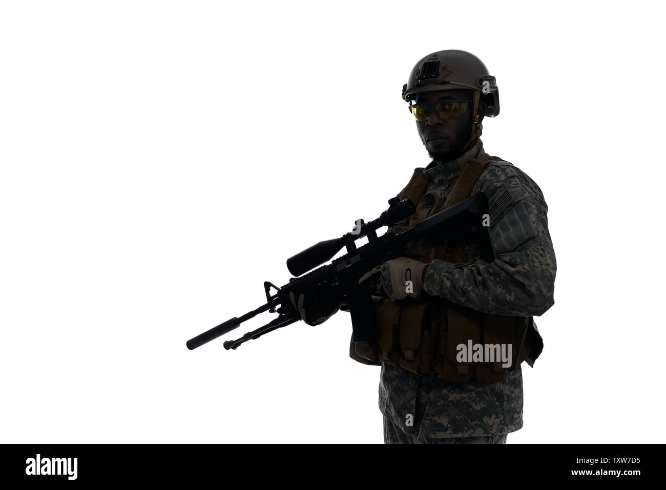 Silhouette of soldier wearing body armour and helmet holding modern weapon in hands and keeping position for fight. Confident male from American army with best weapon. White studio background. Stock Photo