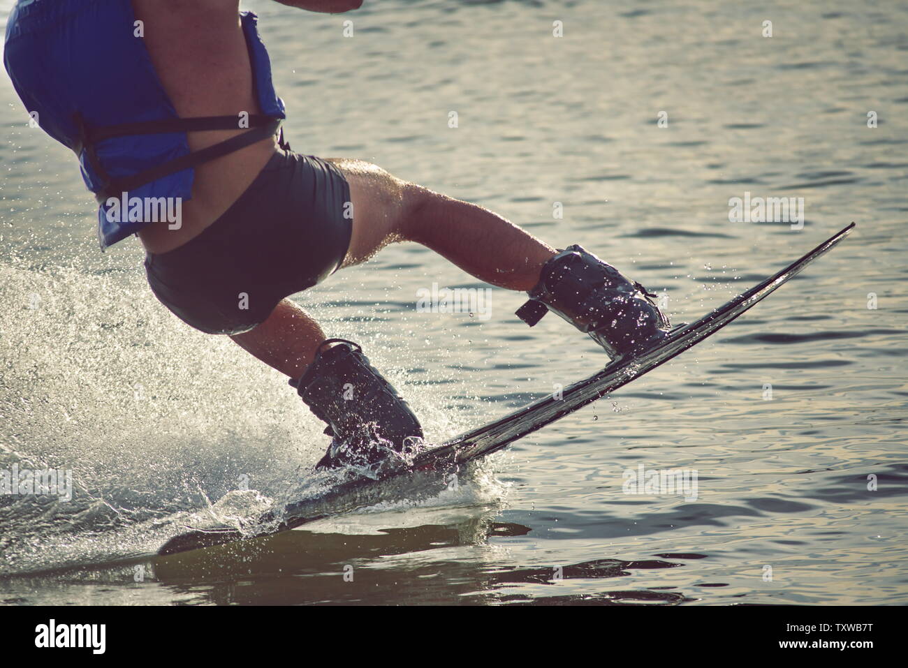 Surfer wakeboarding an jumping Ollie at golden sunset. Skilled