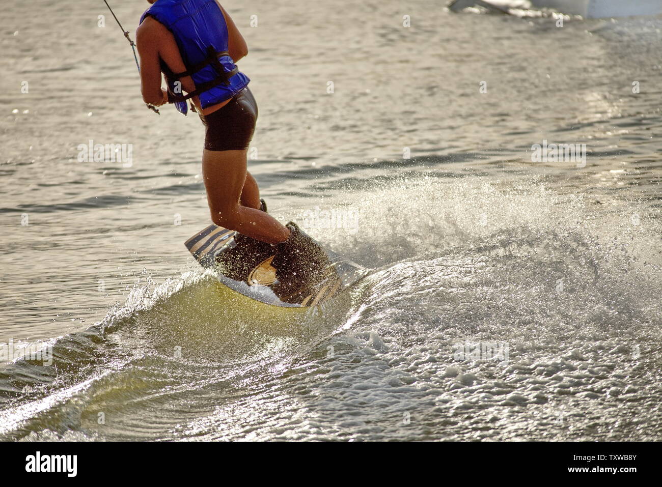 Surfer wakeboarding an jumping Ollie at golden sunset. Skilled