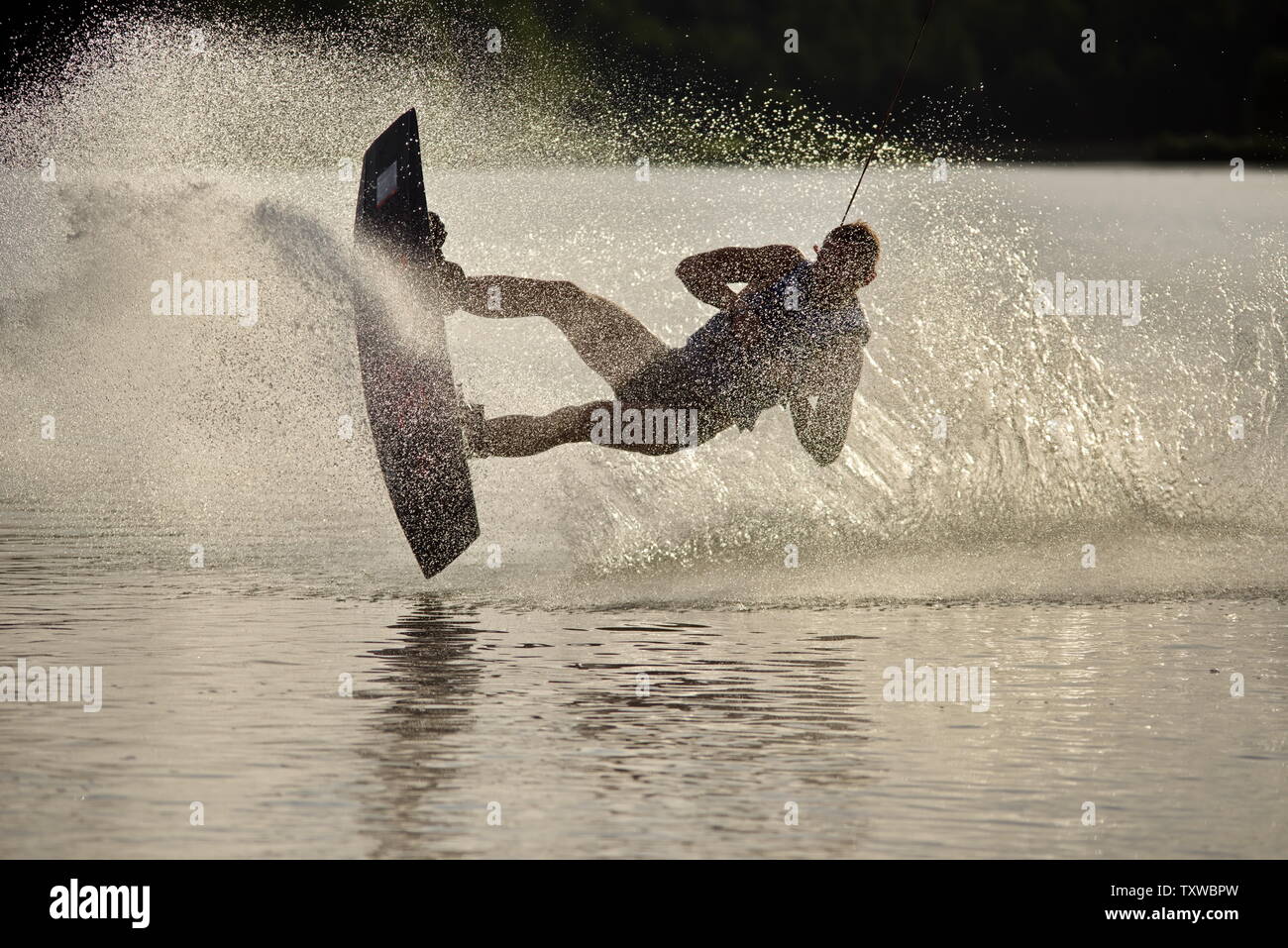 Surfer wakeboarding an jumping Ollie at golden sunset. Skilled