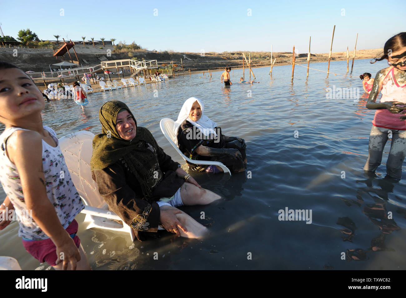 Palestinians Sit In The Dead Sea On Plastic Chairs On The