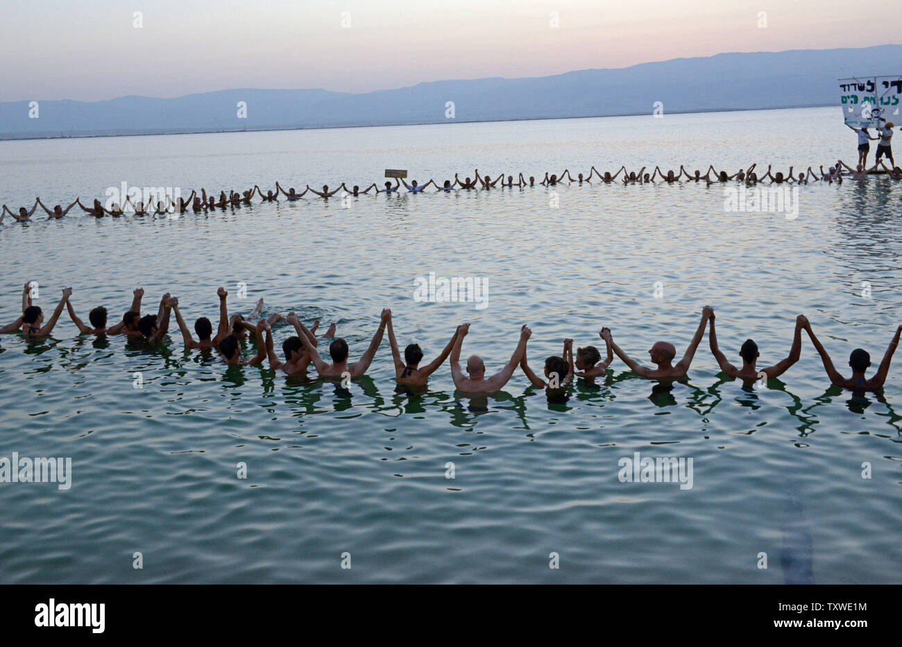 Israeli and international environmental and social activists hold hands in the Dead Sea, during a protest float at dawn against the deterioration of the Dead Sea, in an event organized by U.S. photographer Spencer Tunick, not seen, at Ein Bokek, Israel, September 14, 2012. UPI/Debbie Hill Stock Photo