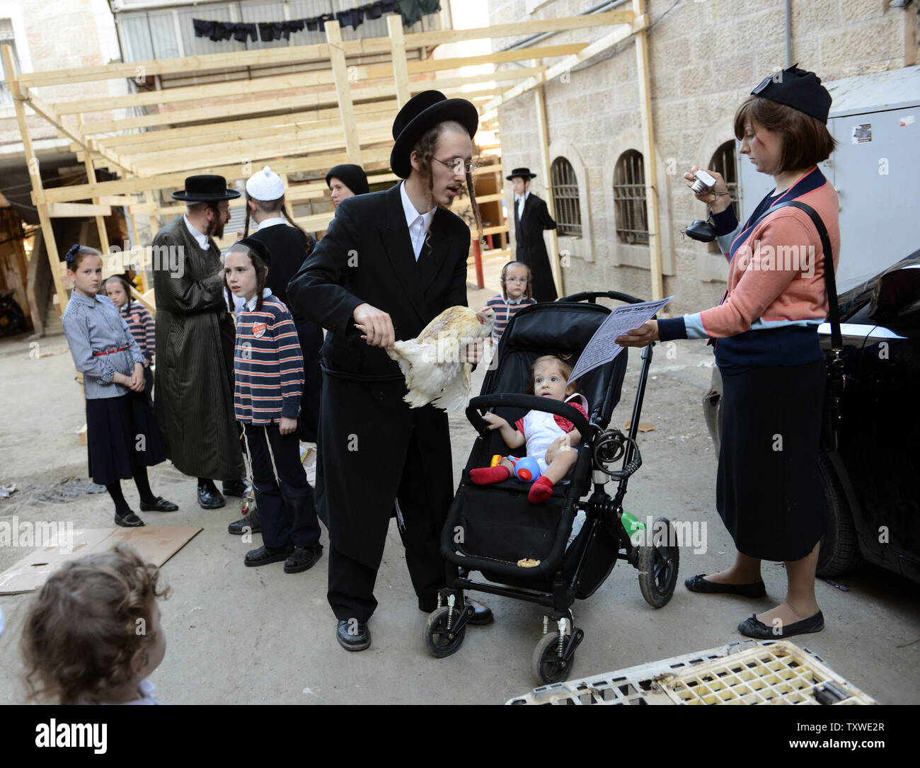 An Ultra-Orthodox Jewish man swings a chicken over a baby in a stroller during the "Kaparot" ceremony in the Mea Shearim neighborhood in Jerusalem, September 23, 2012. Religious Jews prepare for Yom Kippur by performing the ritual of "Kaparot" by reciting a prayer to transfer their sins from the last year to the chicken. Yom Kippur is the holiest day in the Jewish calendar and begins at sunset on September 25. UPI/Debbie Hill Stock Photo