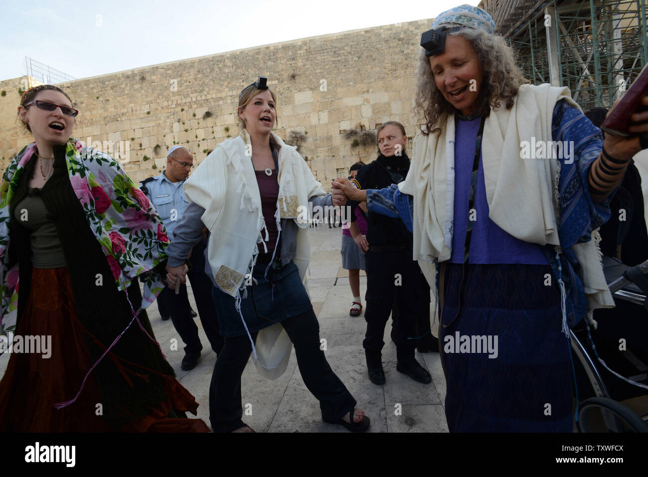 (C) Andrea Wiese from Indiana and (L) Israeli Vonna Devorah Haberman wear  prayer shawls and tefillin while singing and dancing at a prayer service for Rosh Hodesh, which marks the beginning of the Hebrew month of Nisan, at the Western Wall in Jerusalem, Israel, March 12, 2013. More than a hundred women prayed with The Women of the Wall as Ultra-Orthodox men shouted  from the opposite side of the fence separating men and women at the Western Wall. The Women of the Wall calls for the rights of women to pray at the Western Wall, Judaism's holiest site without restrictions as Orthodox Judaism for Stock Photo