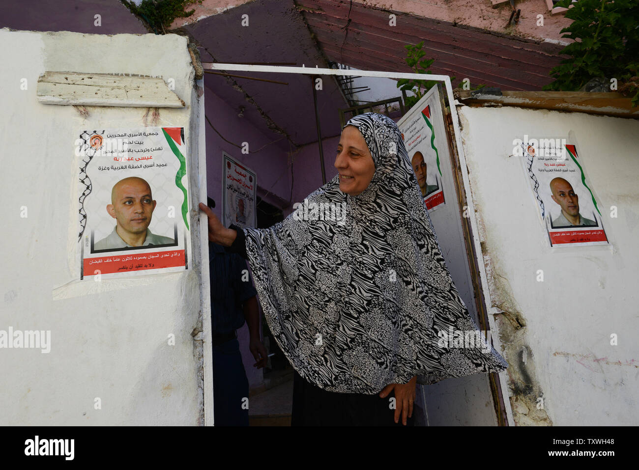 A woman looks at posters of  Palestinian prisoner Issa Abed Rabbo, at the entrance to his home in the Dheisheh Refugee Camp in Bethlehem, West Bank, October 29, 2013. Issa Abed Rabbo has served 30 years in Israeli prison for murdering two Israeli students in 1984. He is one of  26 Palestinian prisoners slated for release.  UPI/Debbie Hill Stock Photo