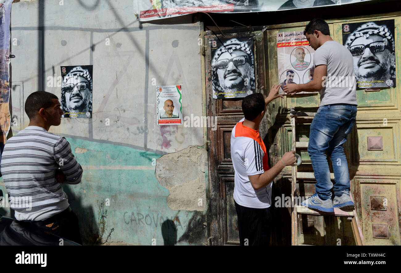 Palestinian youth hang posters of former Palestinian leader Yasser Arafat and  prisoner Issa Abed Rabbo, outside his home in the Dheisheh Refugee Camp in Bethlehem, West Bank, October 29, 2013. Issa Abed Rabbo has served 30 years in Israeli prison for murdering two Israeli students in 1984. He is one of  26 Palestinian prisoners that killed 30 Israelis prior to the 1993 Oslo Accords that is slated for release.  UPI/Debbie Hill Stock Photo