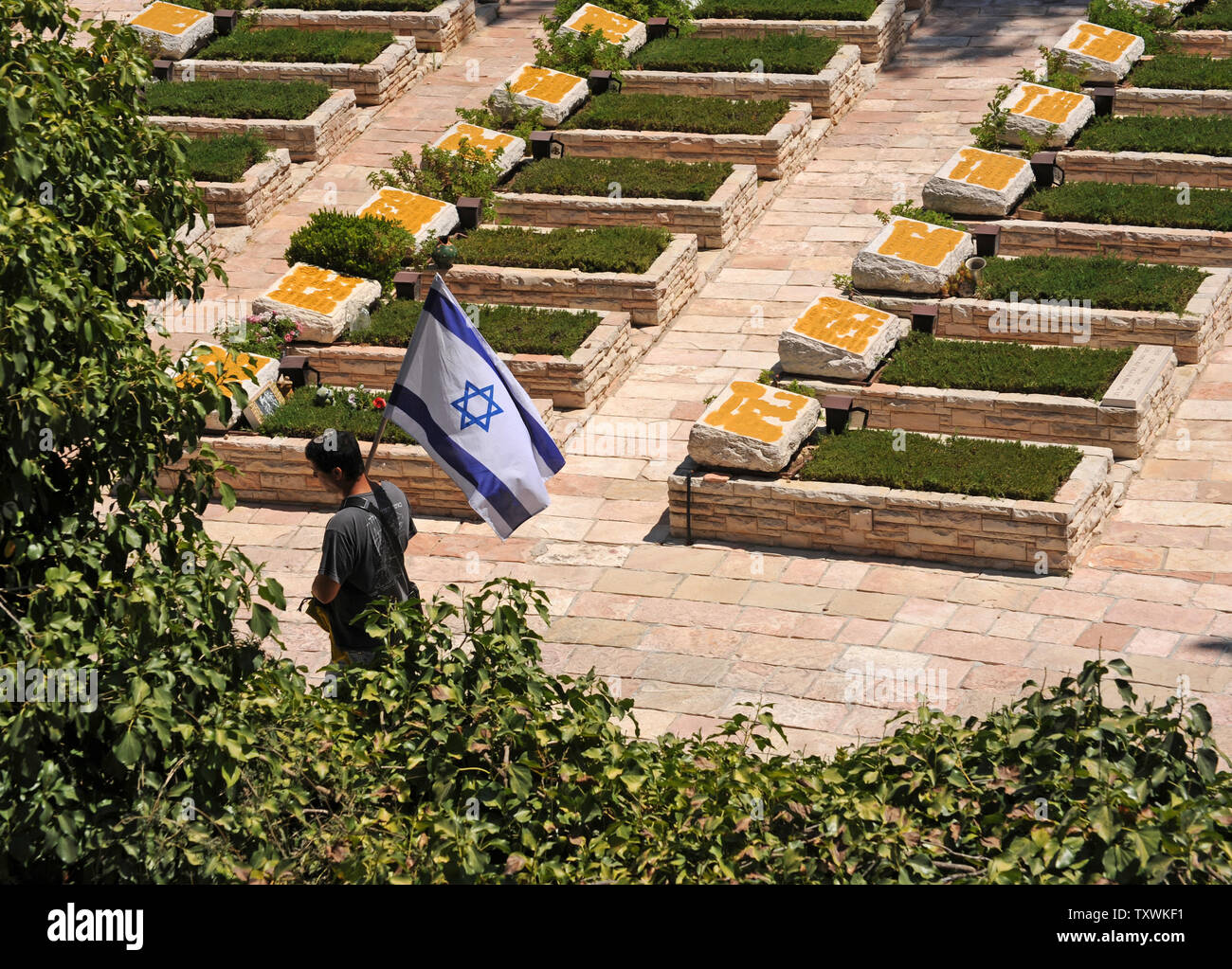 An Israeli carries the national flag during the funeral of American-Israeli soldier Max Steinberg, 24, in the military cemetery on Mt. Herzl in Jerusalem, Israel, July 23, 2014.  Steinberg, a native of Los Angeles, California, immigrated to Israel and enlisted in the Israel Defense Forces in 2012, where he served as a sharpshooter in the elite Golani Brigade. He was among the 13 soldiers killed by Palestinian militants in the Gaza Strip on Sunday. Twenty-nine Israeli troops have been killed since the army launched a ground incursion into Gaza last week. More than 30,000 people attended the fun Stock Photo