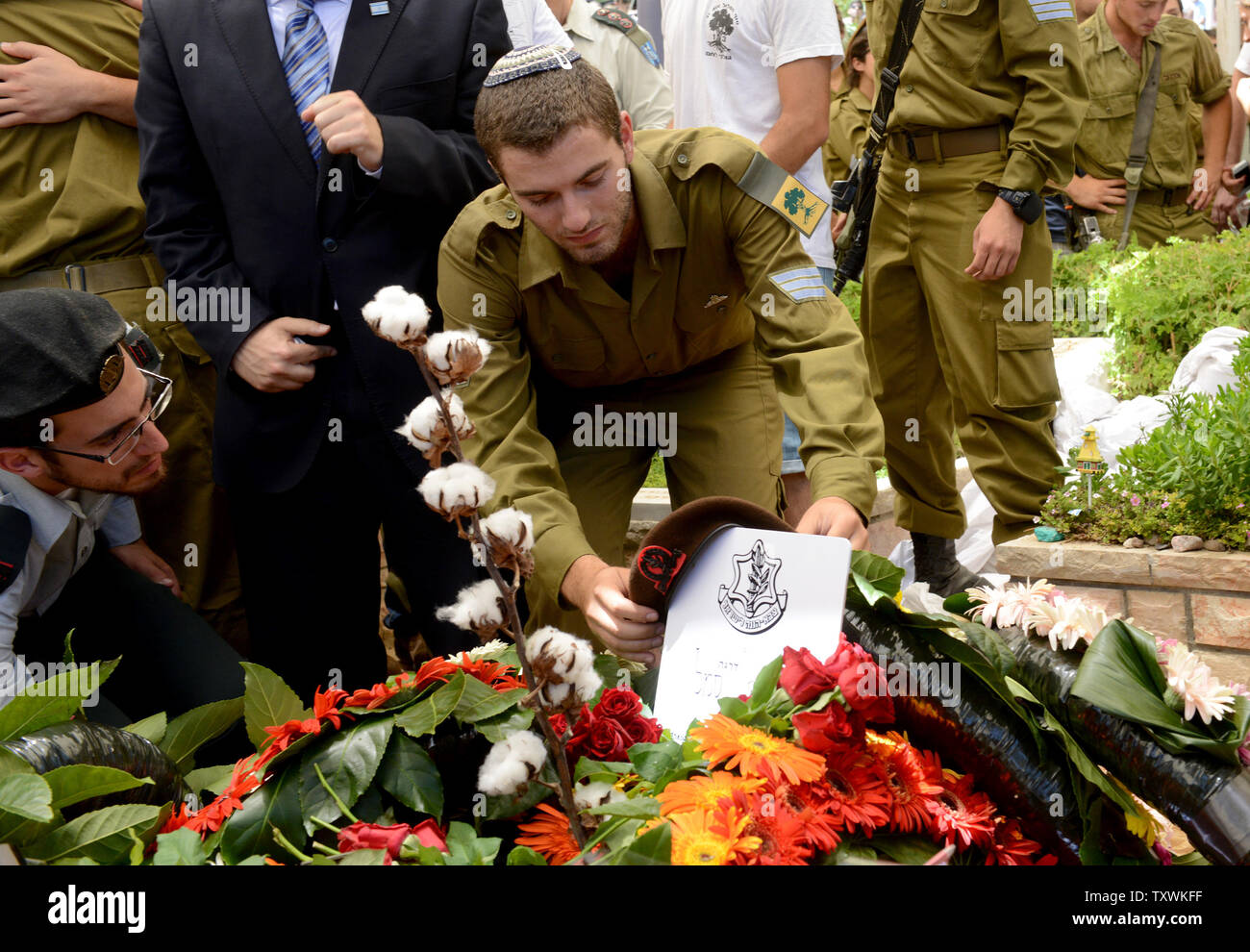 An Israeli soldier places a beret on the flower covered grave of American-Israeli soldier Max Steinberg, 24, at his funeral in the military cemetery on Mt. Herzl in Jerusalem, Israel, July 23, 2014.  Steinberg, a native of Los Angeles, California, immigrated to Israel and enlisted in the Israel Defense Forces in 2012, where he served as a sharpshooter in the elite Golani Brigade. He was among the 13 soldiers killed by Palestinian militants in the Gaza Strip on Sunday. Twenty-nine Israeli troops have been killed since the army launched a ground incursion into Gaza last week. More than 30,000 pe Stock Photo