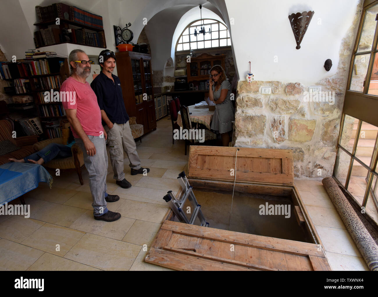 Tal, the owner of the house, stands near a wooden door that leads to a 2,000 year old mikveh, Jewish ritual bath, that was discovered under his living room in the Ein Kerem neighborhood of Jerusalem, Israel, during renovations, July 1, 2015. The Israeli owners of the private house discovered a pair of wooden doors beneath a rug which led to the ancient ritual bath. Archeologist say the discovery is important since Ein Kerem is considered a place sacred to Christianity where according to the New Testament, John the Baptist was born and where his pregnant mother Elizabeth met Mary, mother of Jes Stock Photo