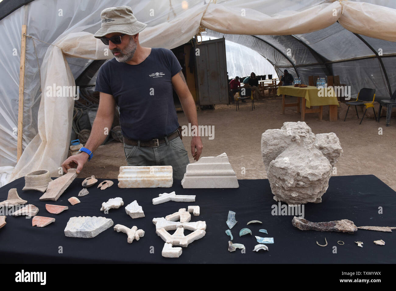 Naftali Aizik, an archeologist with the Israel Antiquities Authority, looks at artifacts discovered in an 1,5000 year old Byzantine Period monastery and church uncovered during large scale excavations in Beit Shemesh, Israel, December 20, 2017. The Byzantine structure was discovered during excavations prior to the expansion of Ramat Beit Shemesh for housing. The marble base is engraved with a Maltese cross. Artifacts were found and a number of architectural elements including a marble pillar base decorated with crosses and marble window screens. The artifacts found may indicate that the site w Stock Photo