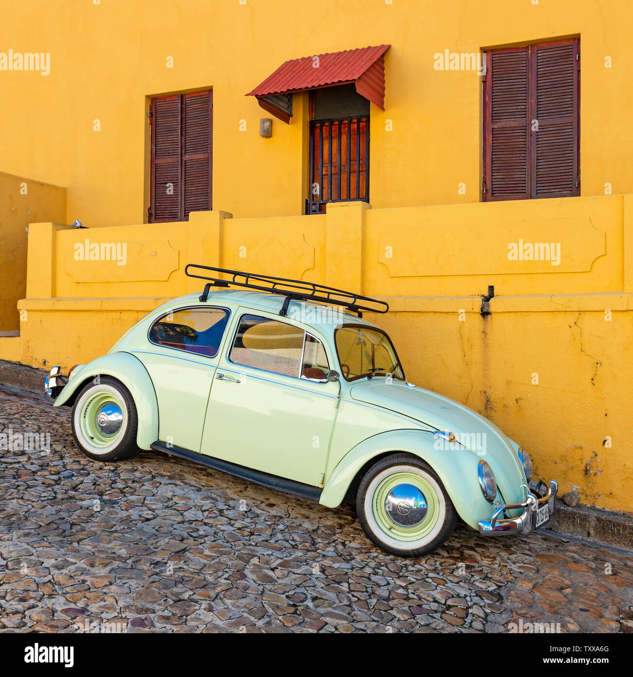 Square photograph of a renovated vintage car or old timer in a colourful street with orange facade of Bo Kaap district, Cape Town, South Africa. Stock Photo