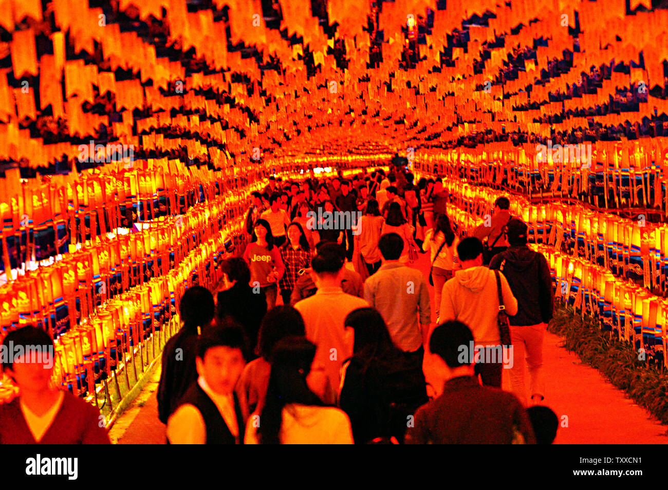Visitors glow red in a tunnel of festival lanterns at the Jinju Namgang