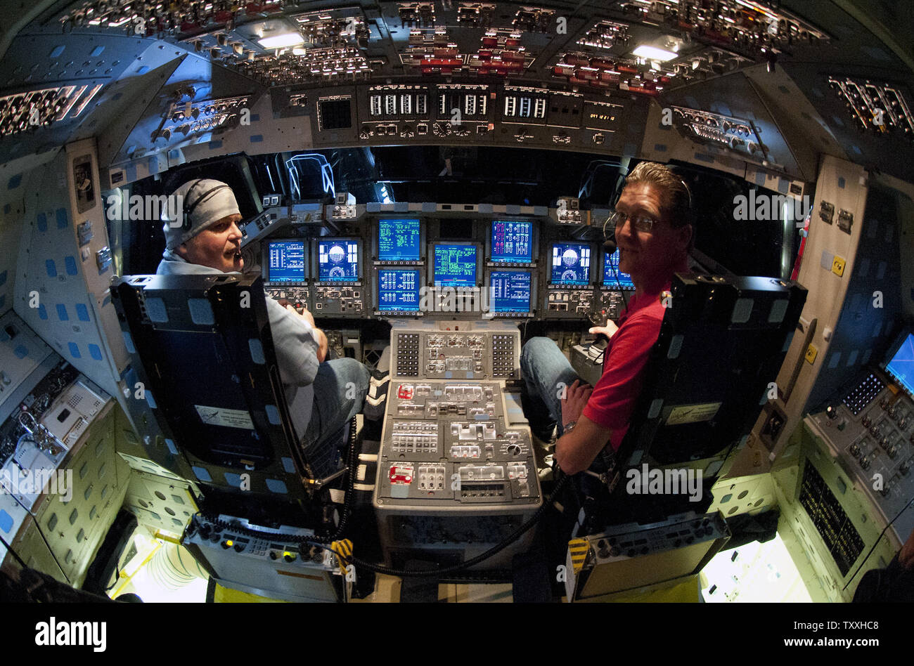 The cockpit displays illuminate the flight deck of NASA's space shuttle  "Endeavour" as two of her "SCOs" or Spacecraft Operators, William Powers  (l) and Charles Beason sit in the Commander's (l) and