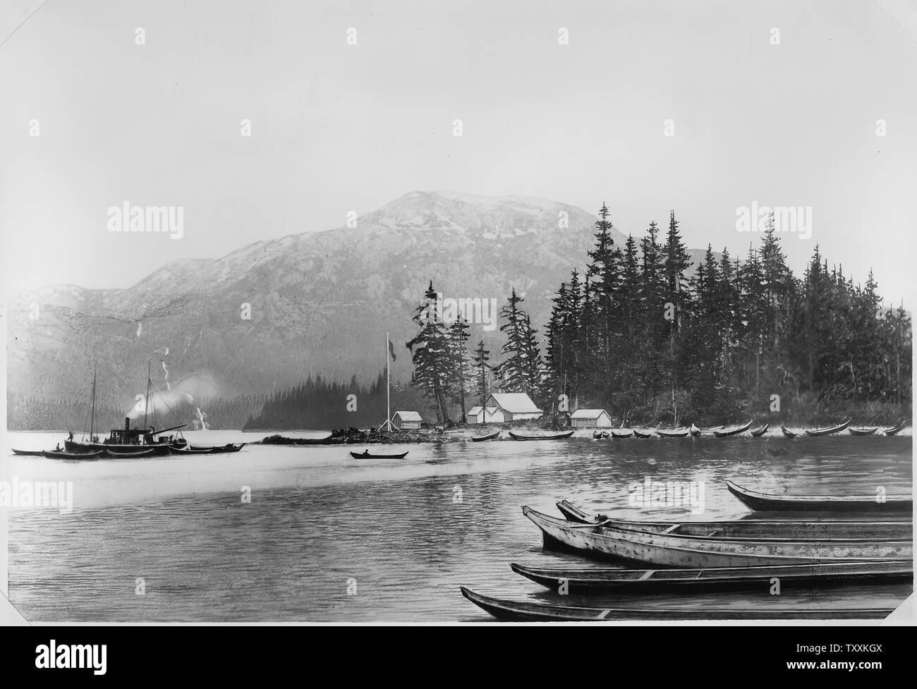 Building shown was the first erected on Annette Island and William Duncan's first residence. To the left, Methodist Mission Boat Glad Tidings, about to return to Fort Simpson (September 1887), after towing the Metlakahtlans to their new home in Alaska. Stock Photo