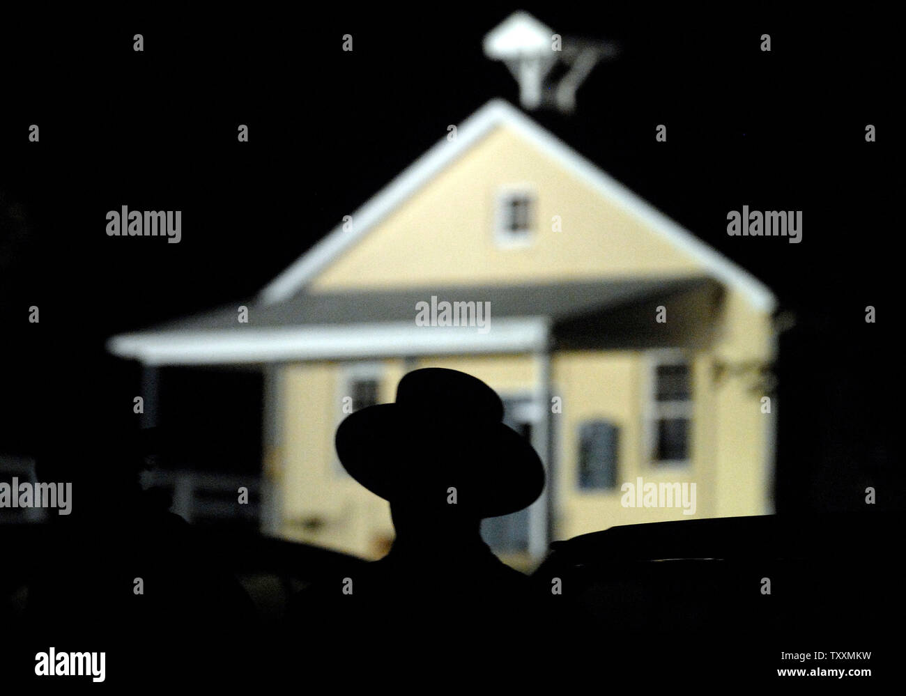 An Amish man is silhouetted  by the Nickel Mines School House as the police continue collective evidence hours after a gunman stormed the school, barricading himself inside and killing several girls 'execution style' before turning the gun on himself, in Nickel Mines, PA on October 2, 2006. (UPI Photo/Kevin Dietsch) Stock Photo