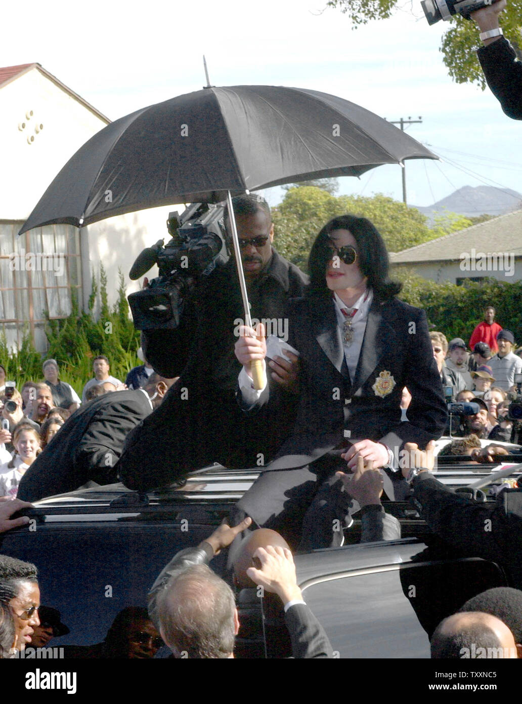 Pop star Michael Jackson climbs down from his SUV after leaving the courthouse in Santa Maria, California January 16, 2004. Jackson pleaded innocent to child molestation charges on Friday during a hearing in which a California judge gave the onetime 'King of Pop' a stern lecture for showing up late and slapped a gag order on his high-profile legal team. The two men with Jackson are his personal videographers.  (UPI Photo/Jim Ruymen) Stock Photo