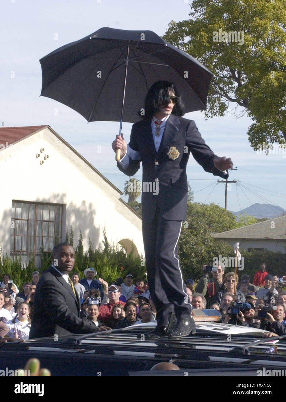 Pop star Michael Jackson dances atop  his SUV after leaving the courthouse in Santa Maria, California January 16, 2004. Jackson pleaded innocent to child molestation charges on Friday during a hearing in which a California judge gave the onetime 'King of Pop' a stern lecture for showing up late and slapped a gag order on his high-profile legal team. The two men with Jackson are his personal videographers.  (UPI Photo/Jim Ruymen) Stock Photo