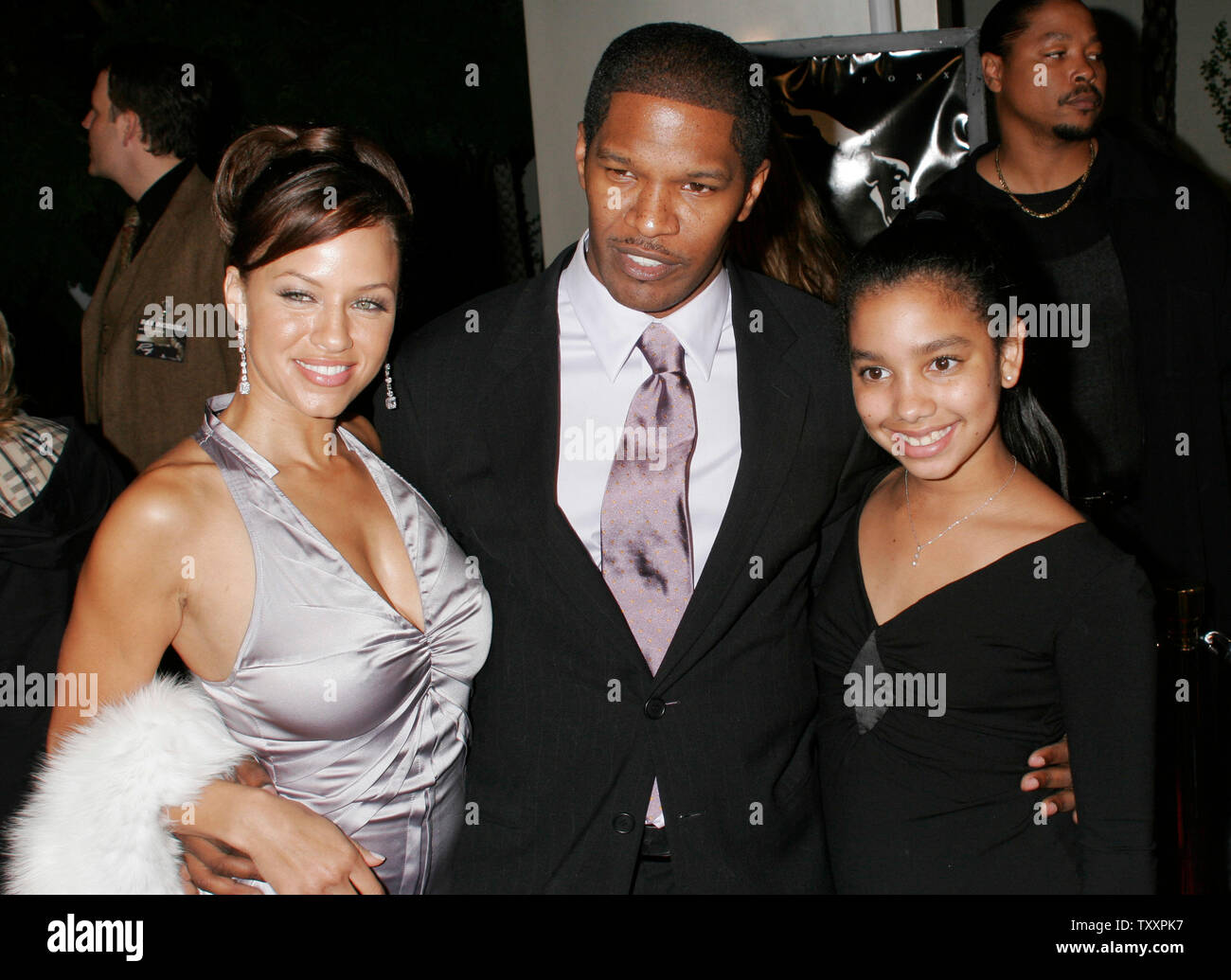 Actor Jamie Foxx, center, his girlfriend, Leila Arcieri (L) and his daughter, Corinne (R) pose for photographers at the premiere of the new  film 'Ray' about the life and music of the late singer Ray Charles in Los Angeles,  October 19, 2004. The film starring Foxx as Ray Charles, opens in the United States October 29. (UPI Photo/Francis Specker) Stock Photo