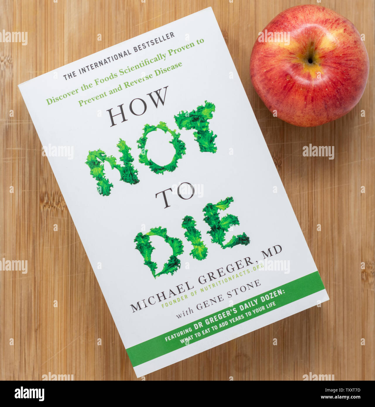 London / UK - June 25th 2019 - Apple and book entitled 'How Not To Die' by Dr Michael Greger. A book containing information about the proven health be Stock Photo