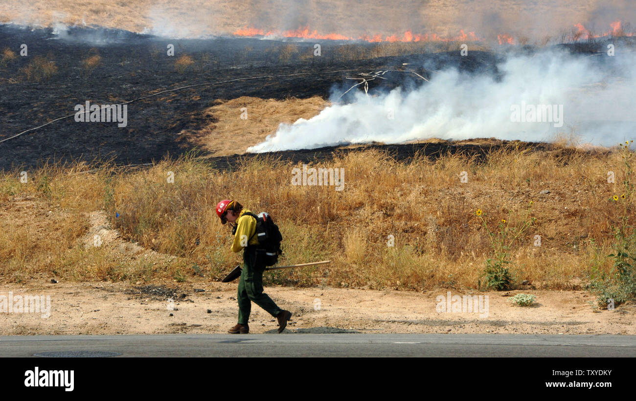 A fireman keeps a watchful eye on a controlled burn to help combat a wildfire in Yucaipa, California on July 16, 2006. Crews battling wildfires that had destroyed 58 homes and blackened more than 110 square miles faced a threat of thunderstorms Sunday that could produce lightning capable of starting new blazes or heavy rain that would flood the newly denuded land. (UPI Photo/Jim Ruymen) Stock Photo