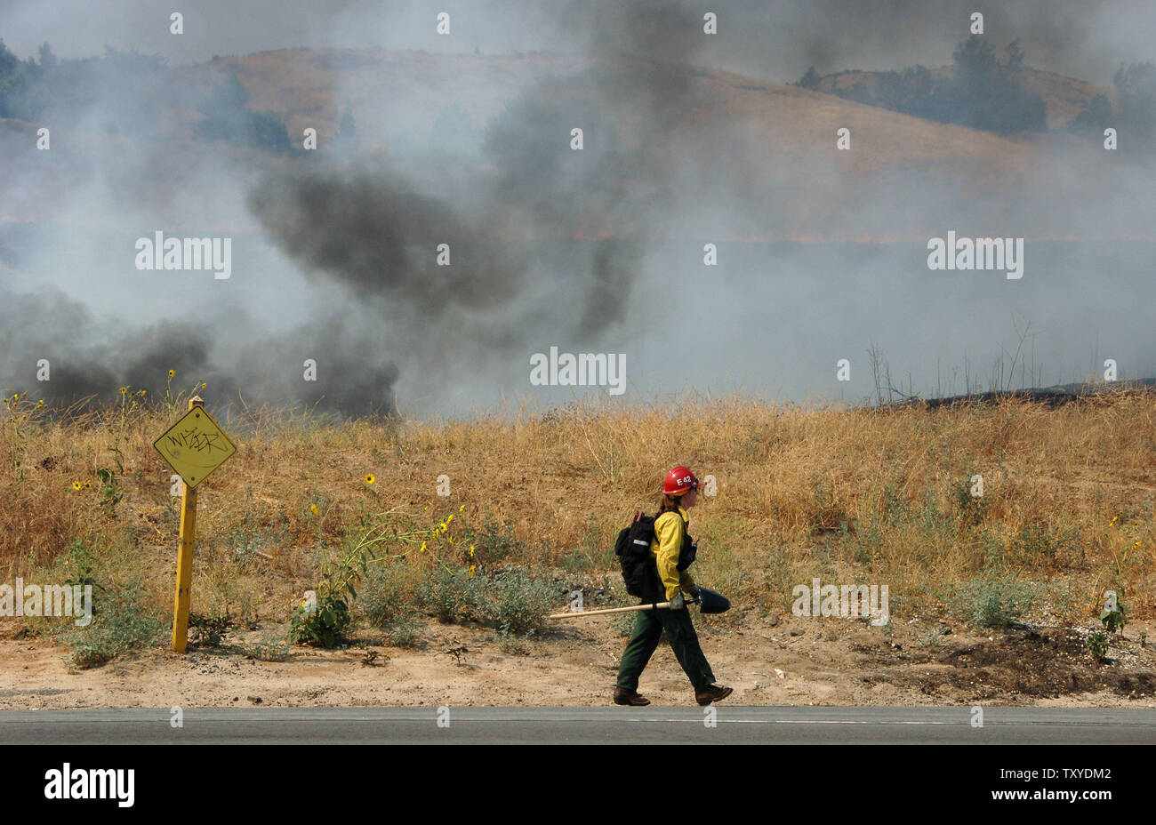 A fireman keeps a watchful eye on a controlled burn to help combat a wildfire in Yucaipa, California on July 16, 2006. Crews battling wildfires that had destroyed 58 homes and blackened more than 110 square miles faced a threat of thunderstorms Sunday that could produce lightning capable of starting new blazes or heavy rain that would flood the newly denuded land. (UPI Photo/Jim Ruymen) Stock Photo