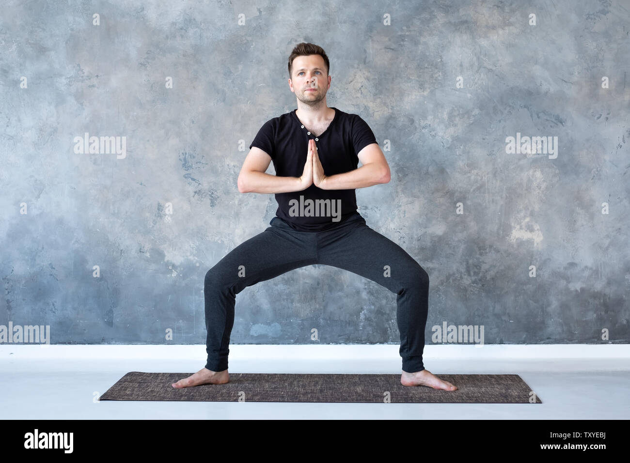 Man working out, yoga, pilates, fitness training, Goddess Pose or rudrasana Stock Photo