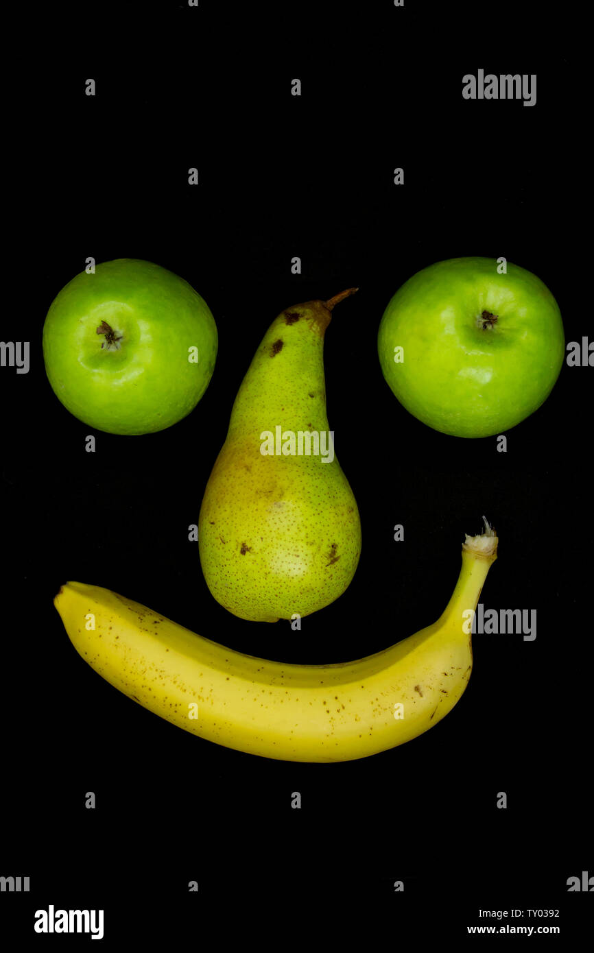 Smiling fruit face with apple eyes isolated on black background Stock Photo