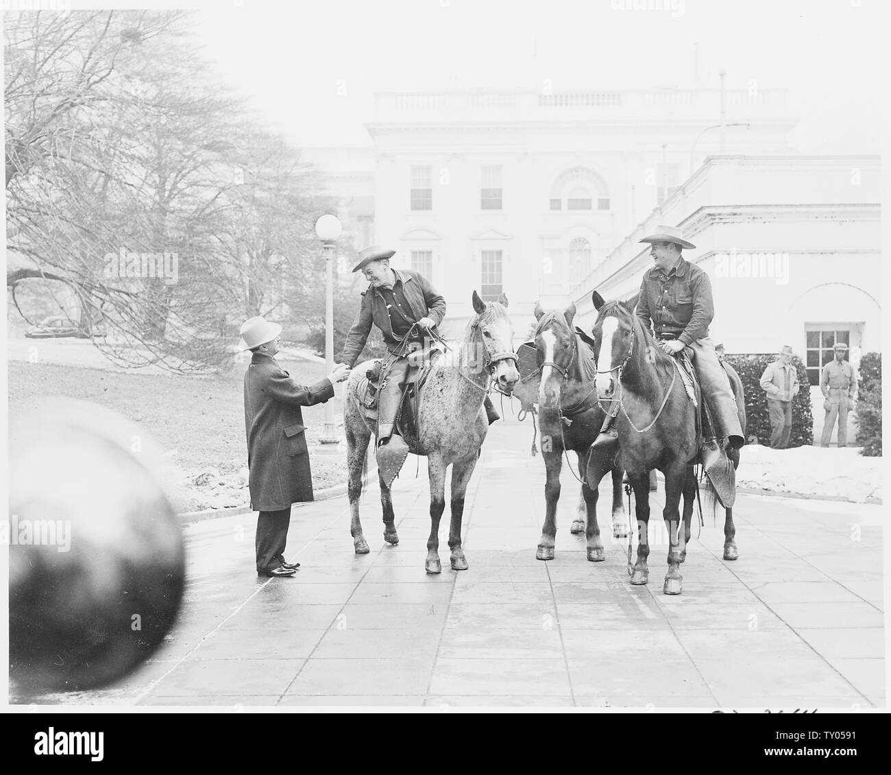 Cross country horseback riders Ned Kennedy and Cecil Cary of Tacoma,  Washington are greeted by an unidentified man as they arrive at the White  House to meet President Truman. They have completed