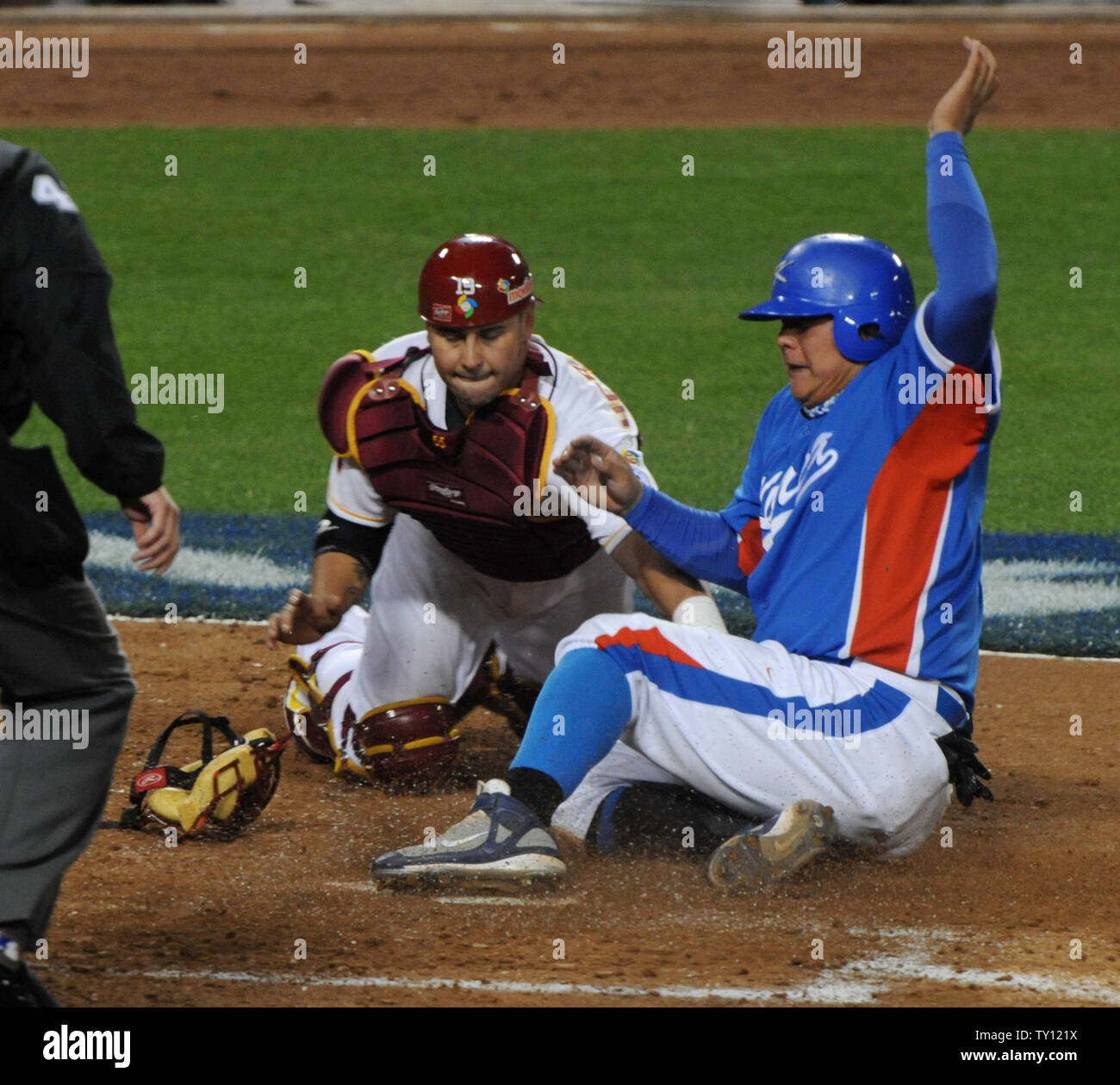 Team Korea's Kim Tae-kyun (R) slides safely into home plate as the throw from the field gets past Team Venezuela's Ramon Hernandez in the sixth inning during the semifinals of the World Baseball Classic in Los Angeles, on March 21, 2009.(UPI Photo/Jim Ruymen) Stock Photo