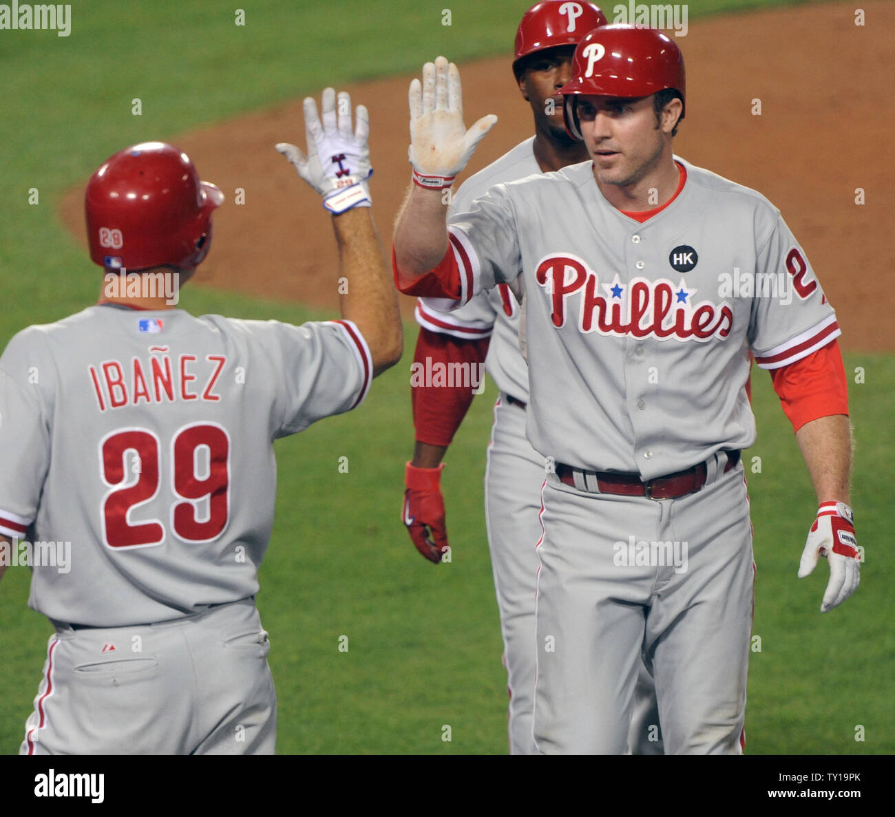 Philadelphia Phillies' Chase Utley (R) and Jimmy Rollins (C) celebrate with  teammate Rail Ibanez after scoring on a Ryan Howard RBI double in the fifth  inning during Game 1 of the National