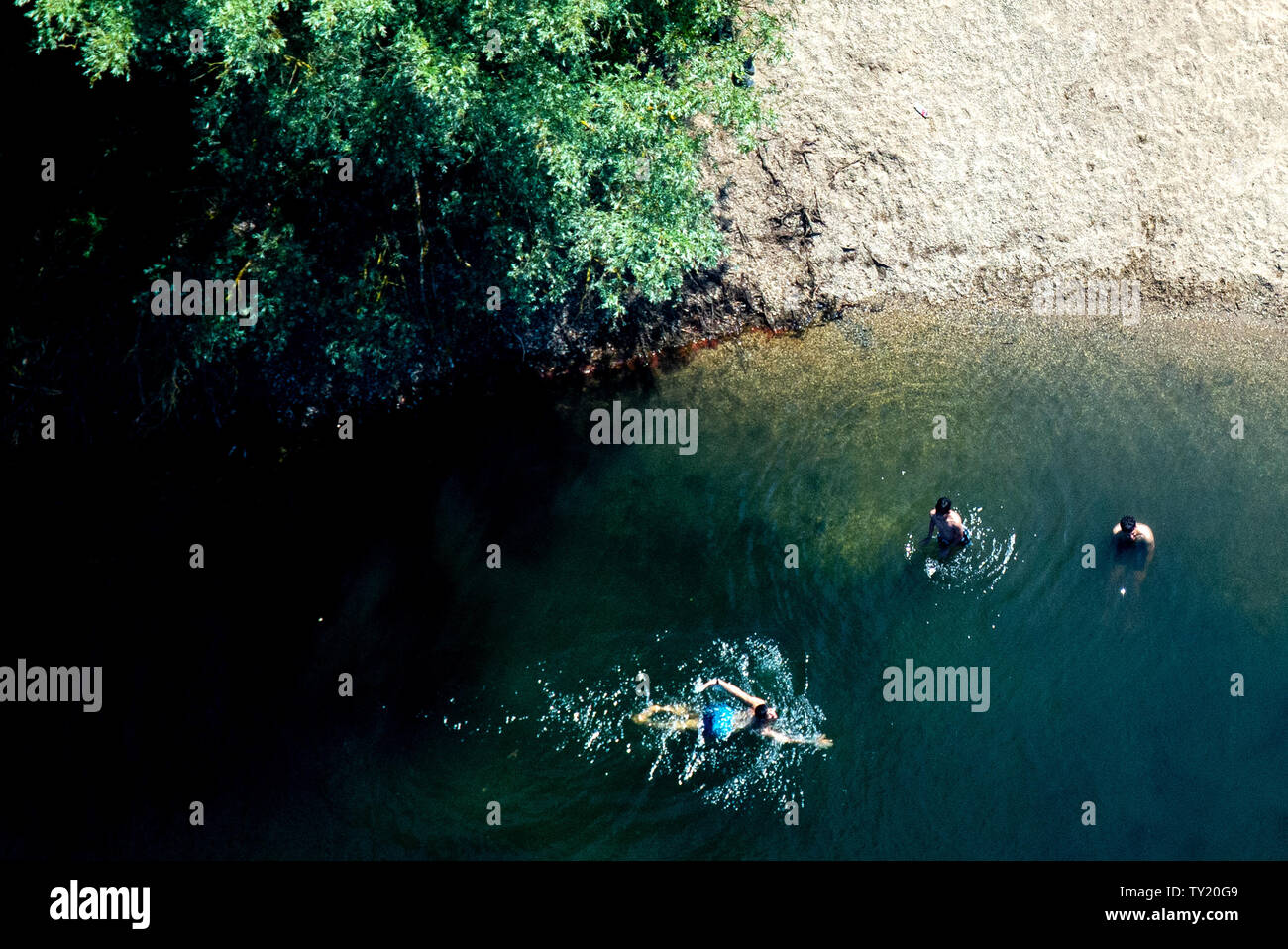 Sarstedt, Germany. 25th June, 2019. Three young men bathe in a lake in the district of