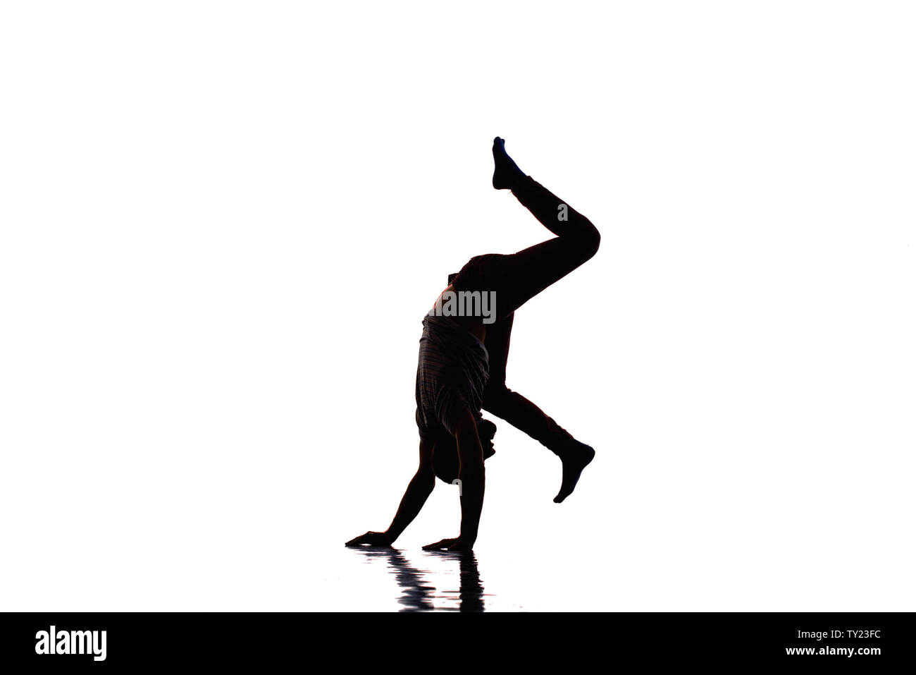 An urban guy is doing handstand in the studio while dancing modern dance Stock Photo