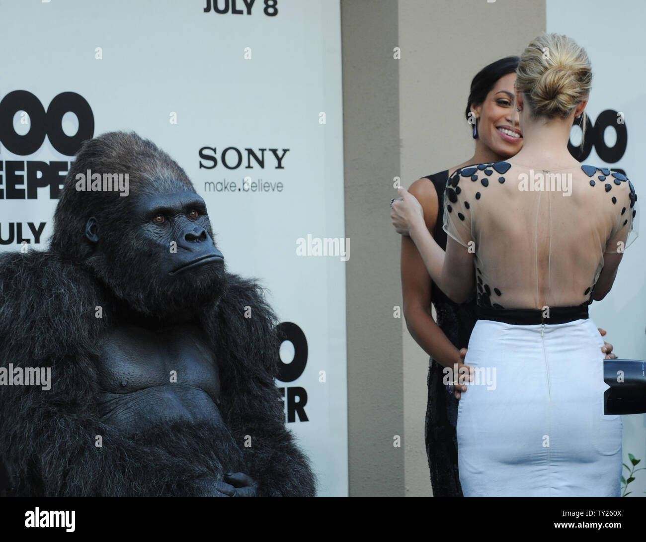 Rosario Dawson (L) and Leslie Bibb, cast members in the motion picture romantic comedy 'Zookeeper', greet each other at the premiere of the film, as an actor in a gorilla costume looks on in Los Angeles on July 6, 2011. UPI/Jim Ruymen Stock Photo