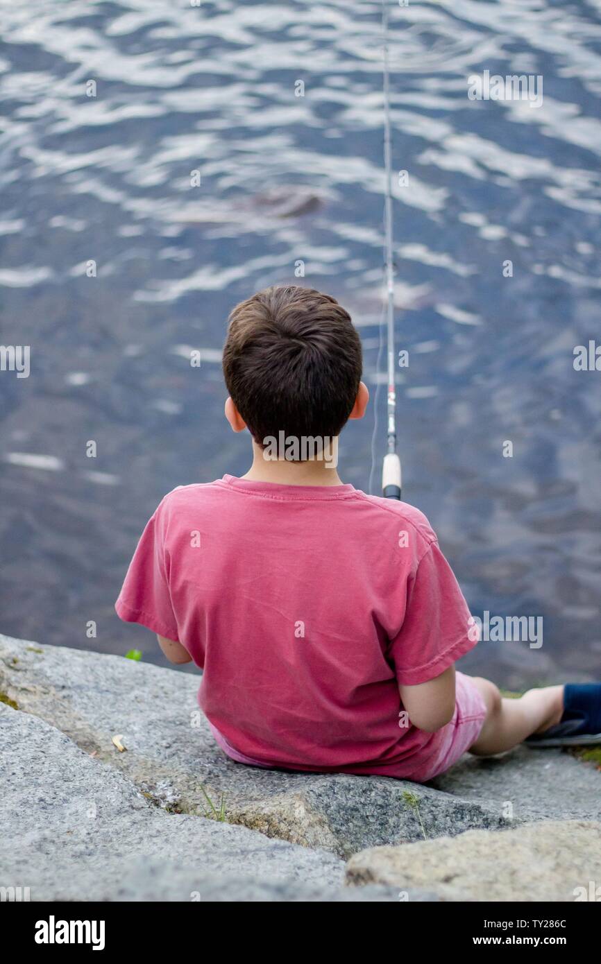 https://c8.alamy.com/comp/TY286C/young-teenager-boy-sitting-on-the-rocks-by-the-river-and-fishing-holding-a-fishing-pole-TY286C.jpg