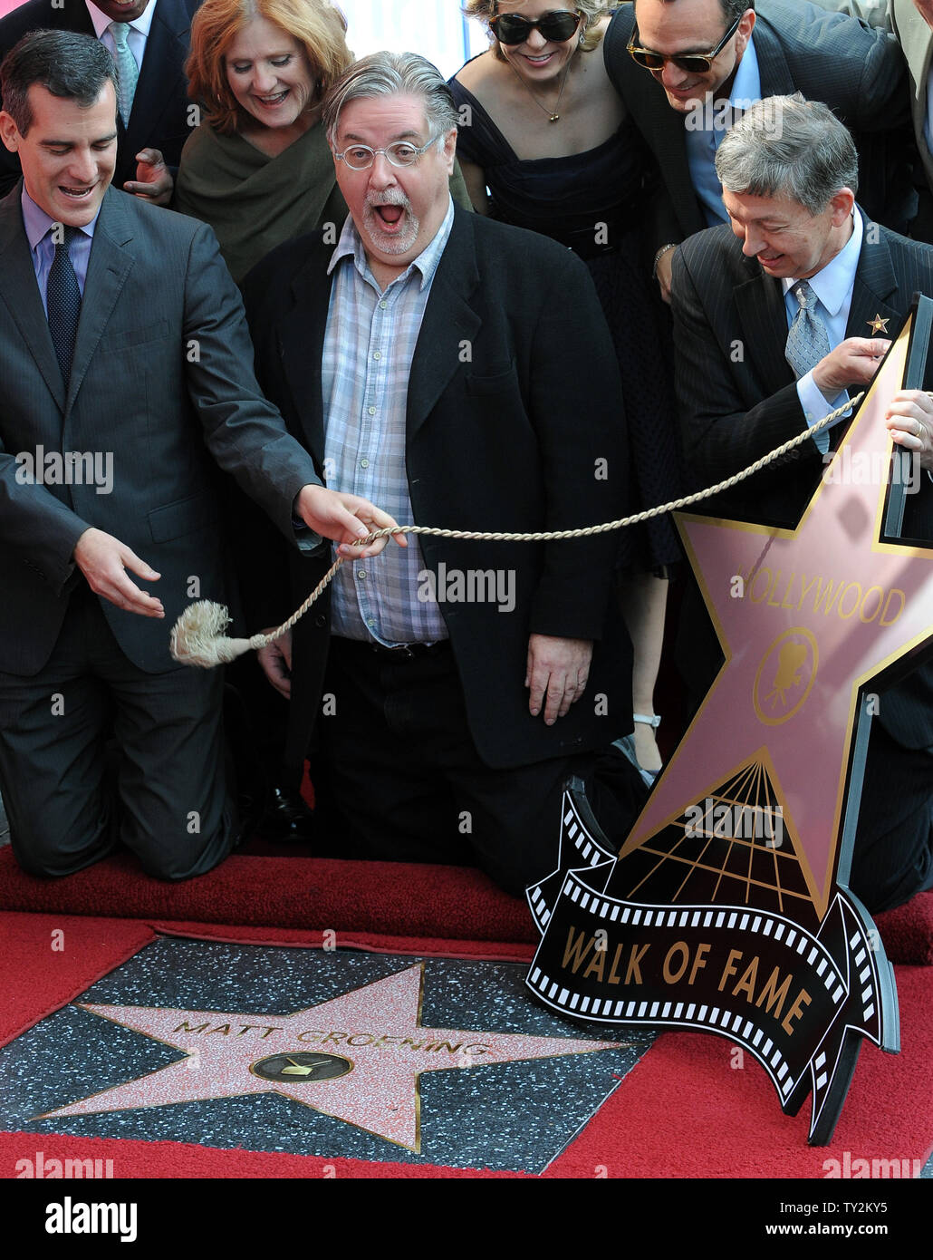 Matt Groening (C), the creator of the longest-running scripted show in  television, poses with two characters from the animated series, Bart  Simpson (L) and Homer Simpson (R), after he was honored with