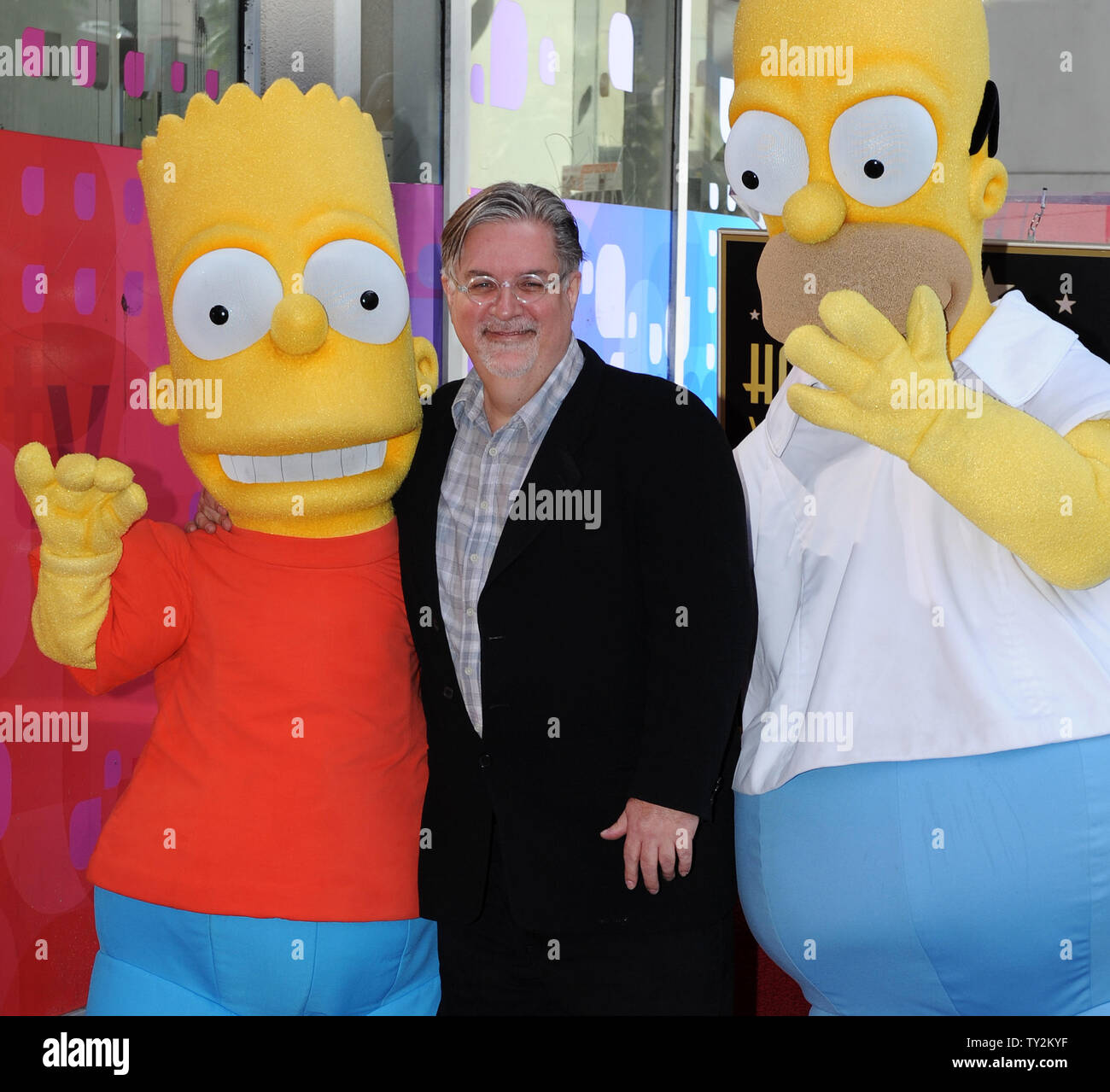 Matt Groening (C), the creator of the longest-running scripted show in  television, poses with two characters from the animated series, Bart  Simpson (L) and Homer Simpson (R), after he was honored with