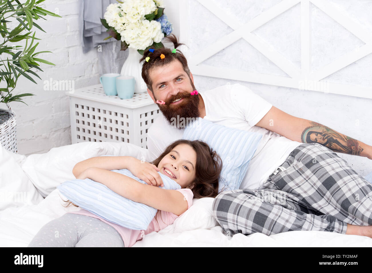 Guy and girl relaxing in bedroom. Pajamas style. Having fun pajamas party.  Happy fatherhood. Man bearded hipster with childish hairstyle colorful  ponytails and daughter in pajamas. Slumber party Stock Photo - Alamy