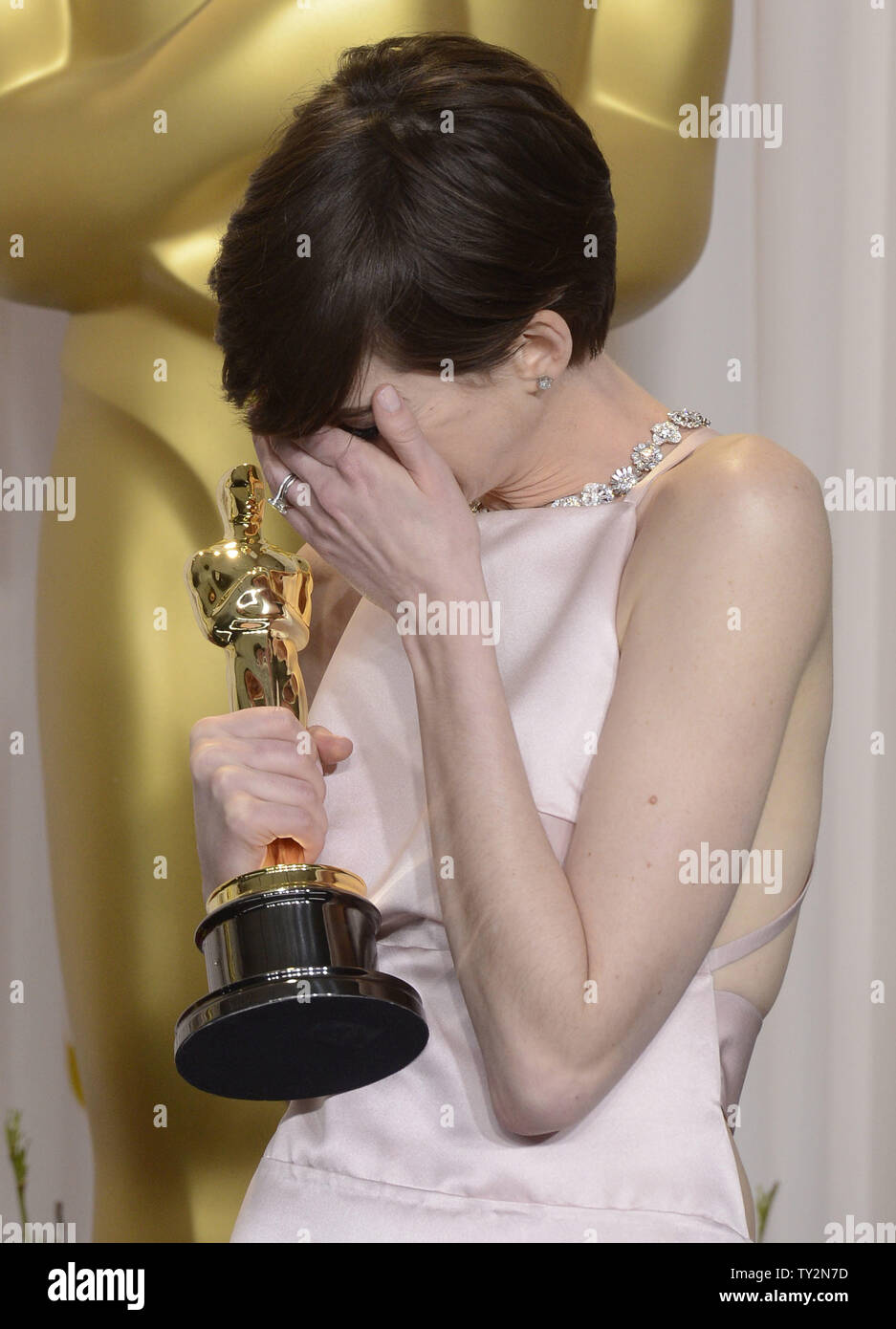 Anne Hathaway becomes emotional as she poses with her Oscar for Performance by an Actress in a Supporting Role for "Les Miserables" backstage at the 85th Academy Awards at the Hollywood and Highlands Center in the Hollywood section of Los Angeles on February 24, 2013. UPI/Phil McCarten Stock Photo