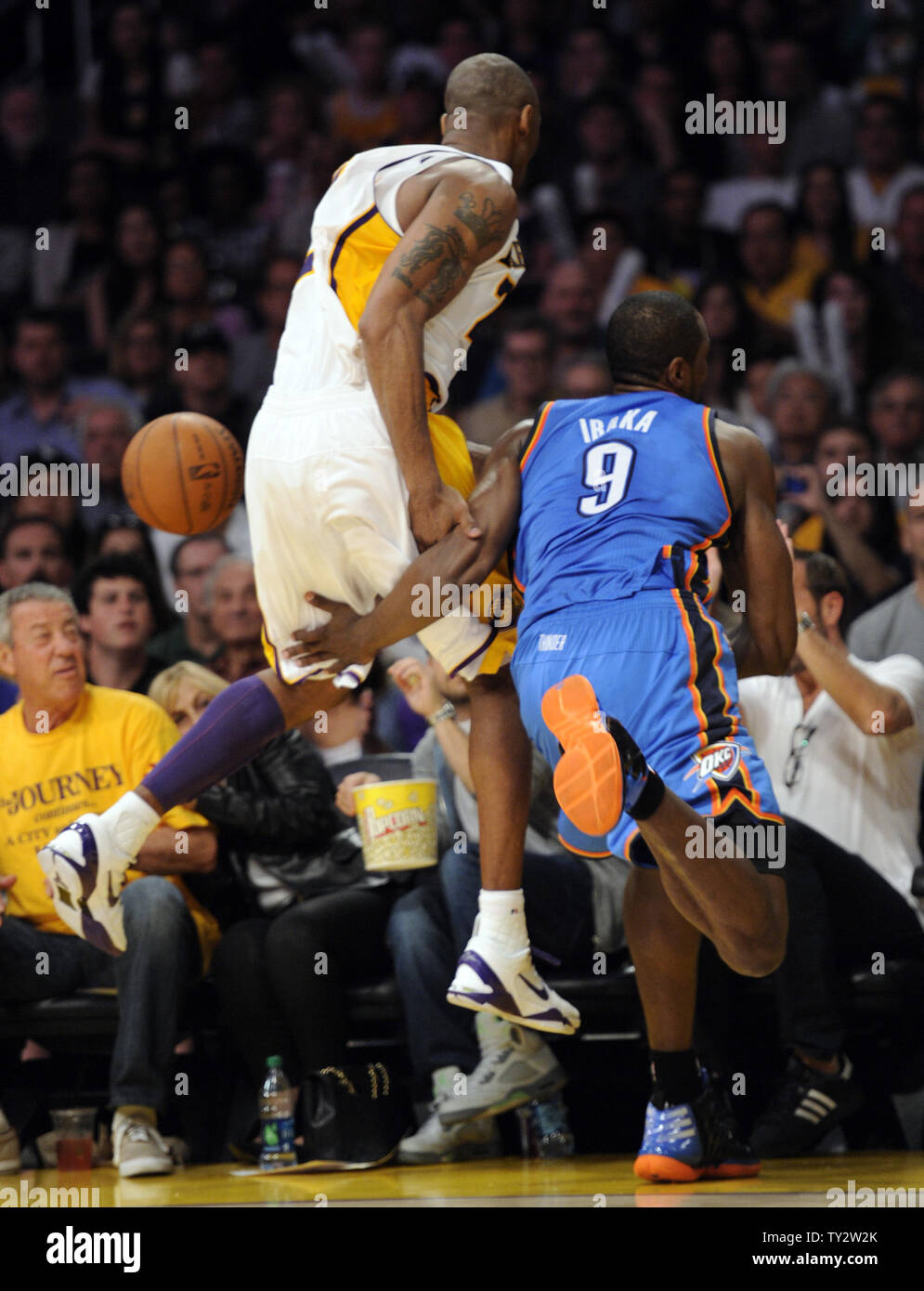 Los Angeles Lakers shooting guard Kobe Bryant (24) and Oklahoma City Thunder power forward Serge Ibaka (9) go for the ball and land in the court side seats in the second half of an NBA basketball game in Los Angeles on April 22, 2012.  The Lakers won 114-106.  UPI/Lori Shepler Stock Photo