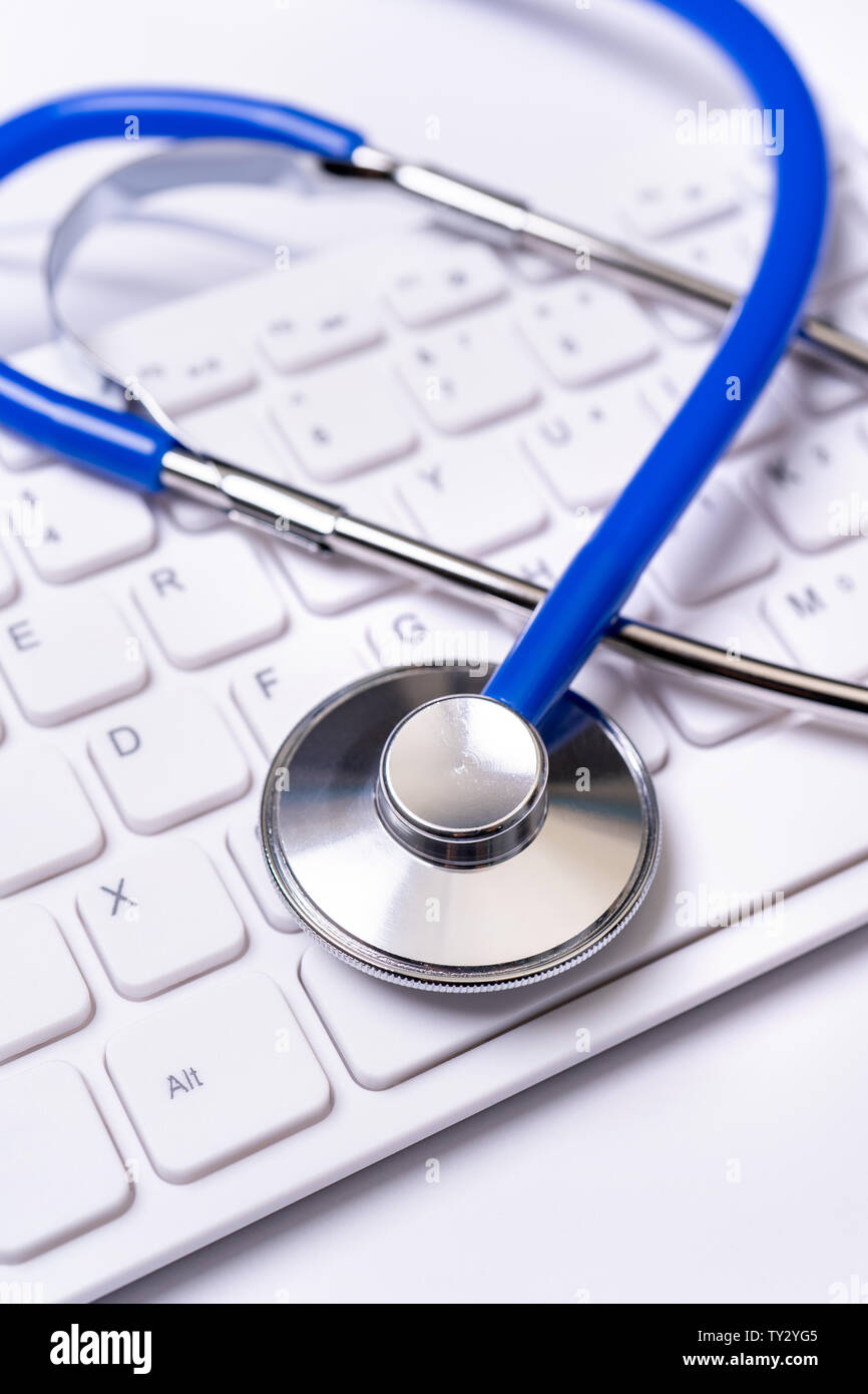 Blue stethoscope on computer keyboard on white table background. Online ...