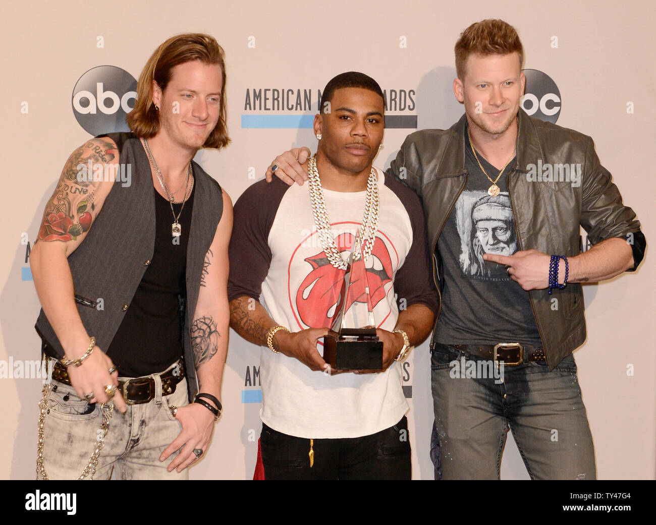 Recording artists Tyler Hubbard (L) and Brian Kelly (R) of music group  Florida Georgia Line and Nelly (C), hold the award they won for Single of  the Year for 'Cruise', backstage at