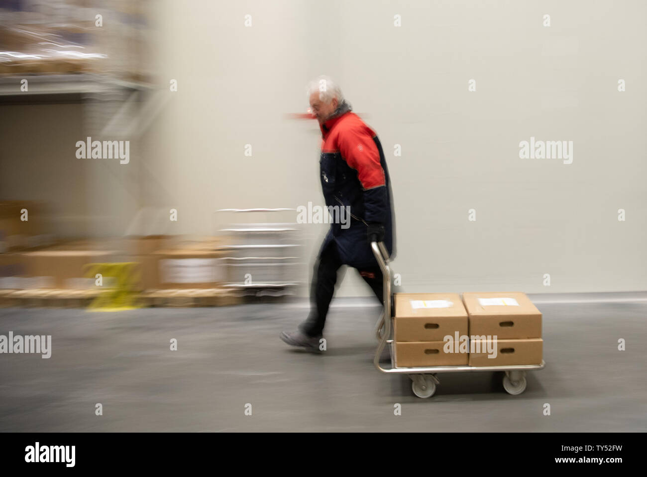 Wiesentheid, Germany. 25th June, 2019. Werner Beck, medical specialist for fresh plasma storage, transports blood plasma in cartons inside a warehouse of the Blutplasma Bank of the Bavarian Red Cross. The temperature in the hall is -42° C. (to dpa "Heat in Germany - cold places in Bavaria") Credit: Nicolas Armer/dpa/Alamy Live News Stock Photo