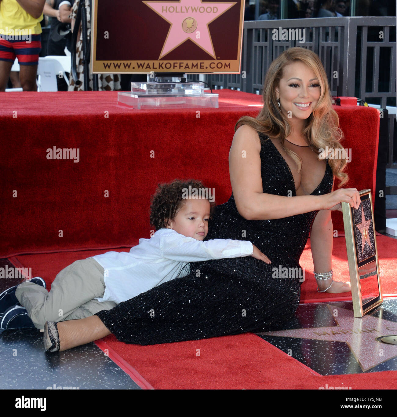 Singer Mariah Carey Holds A Replica Plaque As Her Son Moroccan Cannon Cuddles Up During An 